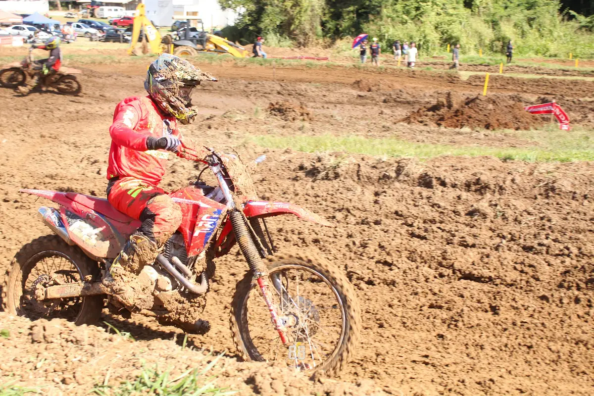 Piloto de vermelho contornando uma curva de lama